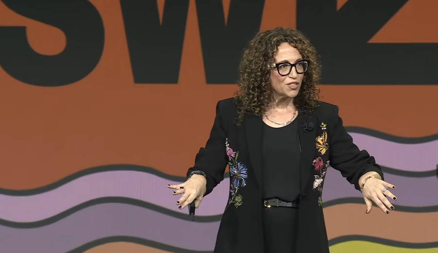 Amy Webb in a black outfit with floral details on a colorful background