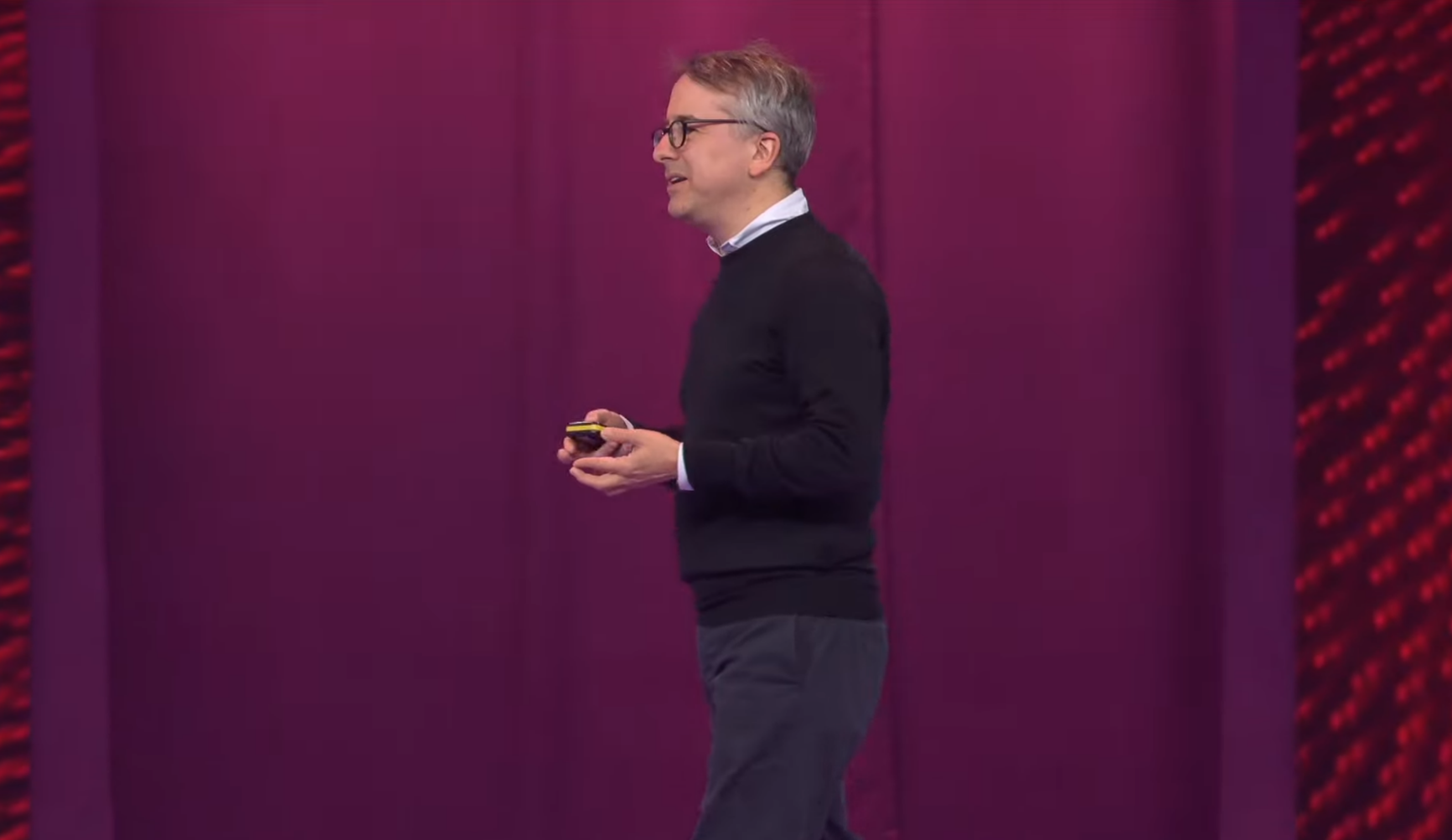 Benedict Evans giving a presentation on a stage with a purple curtain background