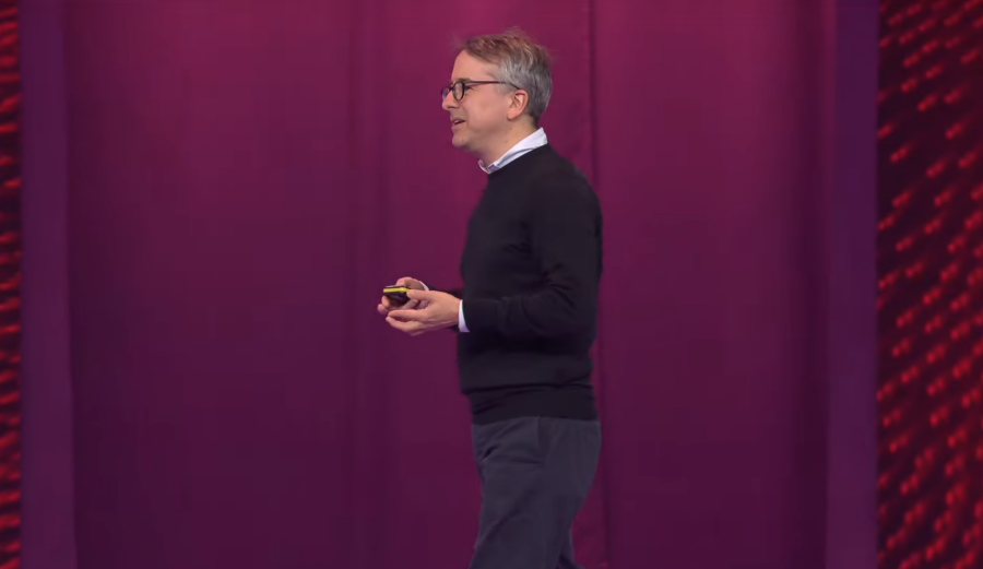 Benedict Evans giving a presentation on a stage with a purple curtain background
