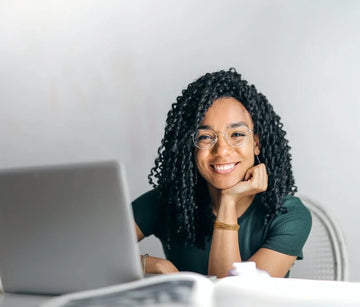 Smiling woman with laptop working on a design presentation looking at camera